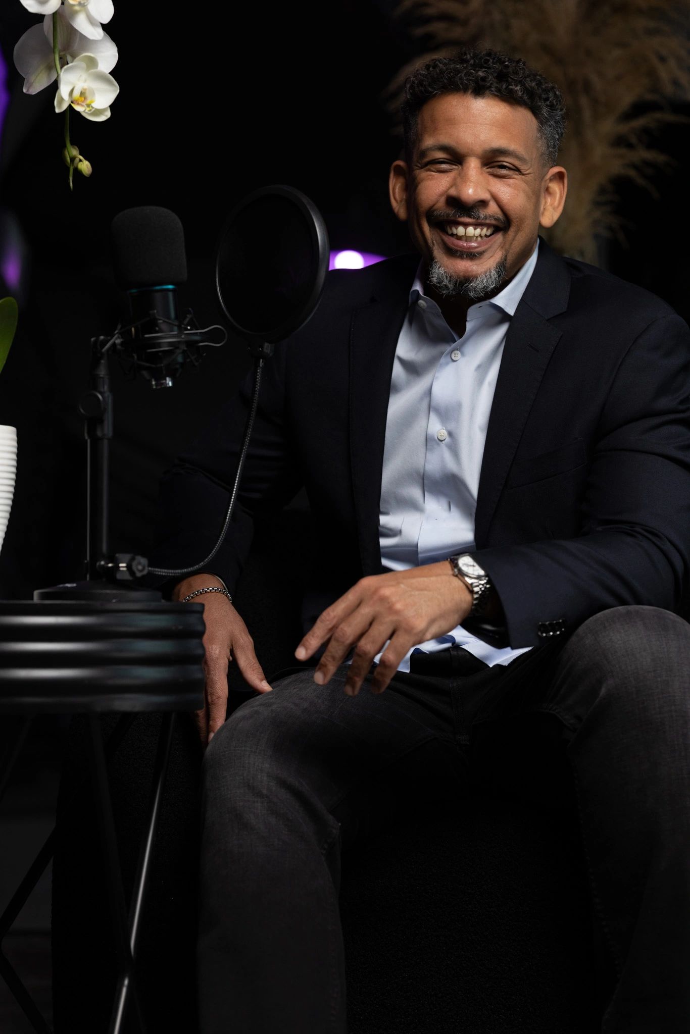 Asa P. Sealy — host of The Strpd Club, seated next to a professional microphone